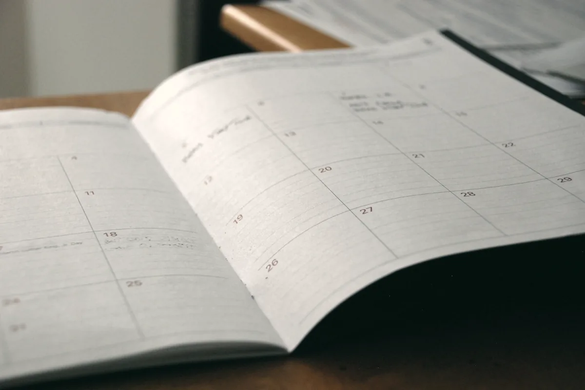 Una agenda de papel abierta sobre un escritorio de madera.